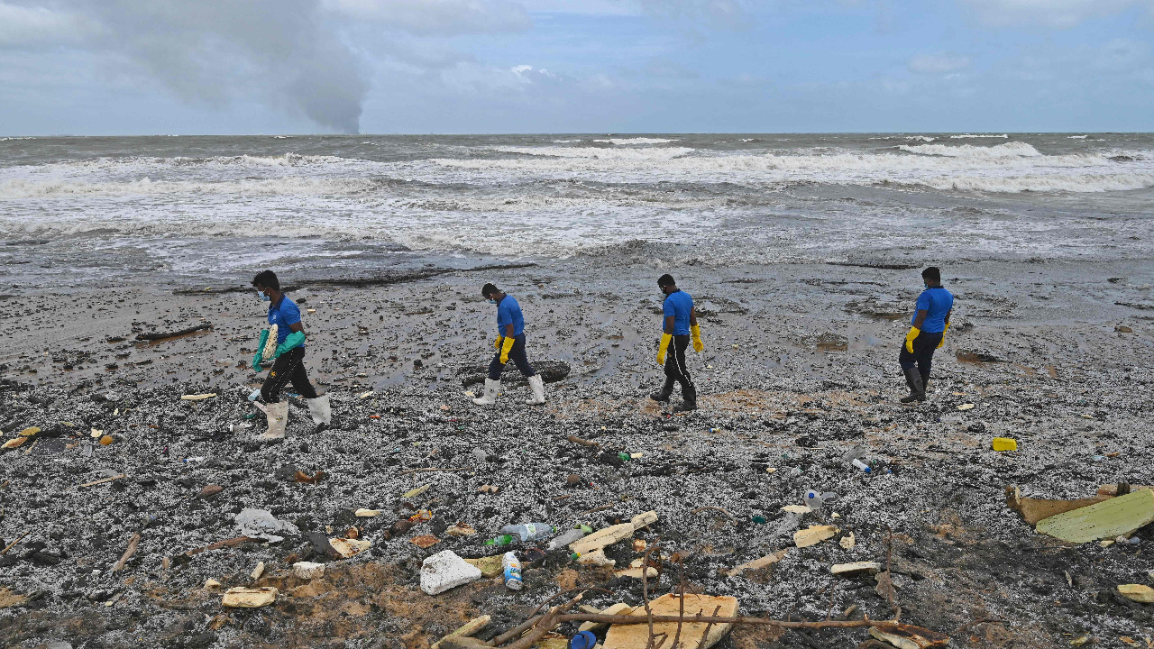 Sri Lankan Navy soldiers work to remove debris washed ashore from the burning ship. Credit: AFP Photo
