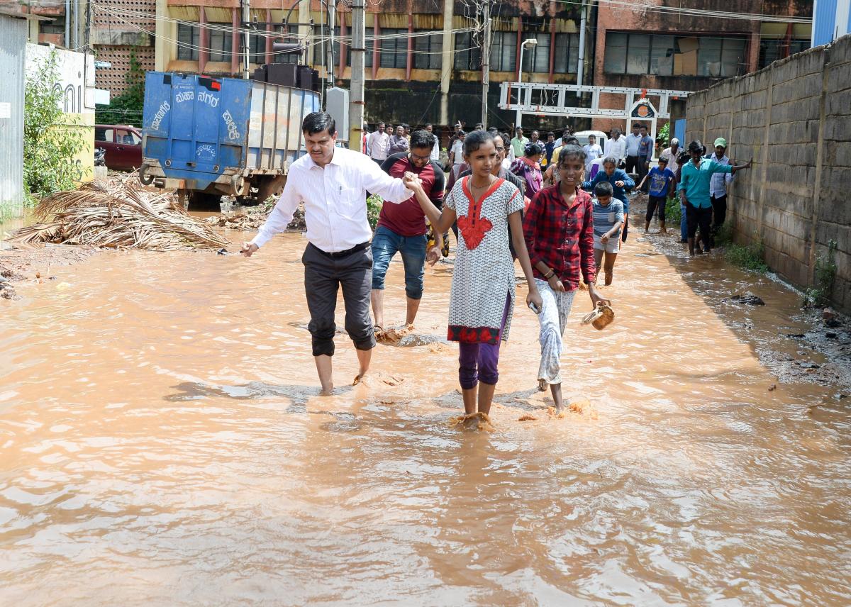 A girl accompanies Davangere Deputy Commissioner Mahantesh Bilagi duiring the latter’s inspection of an inundated area in Davangere.