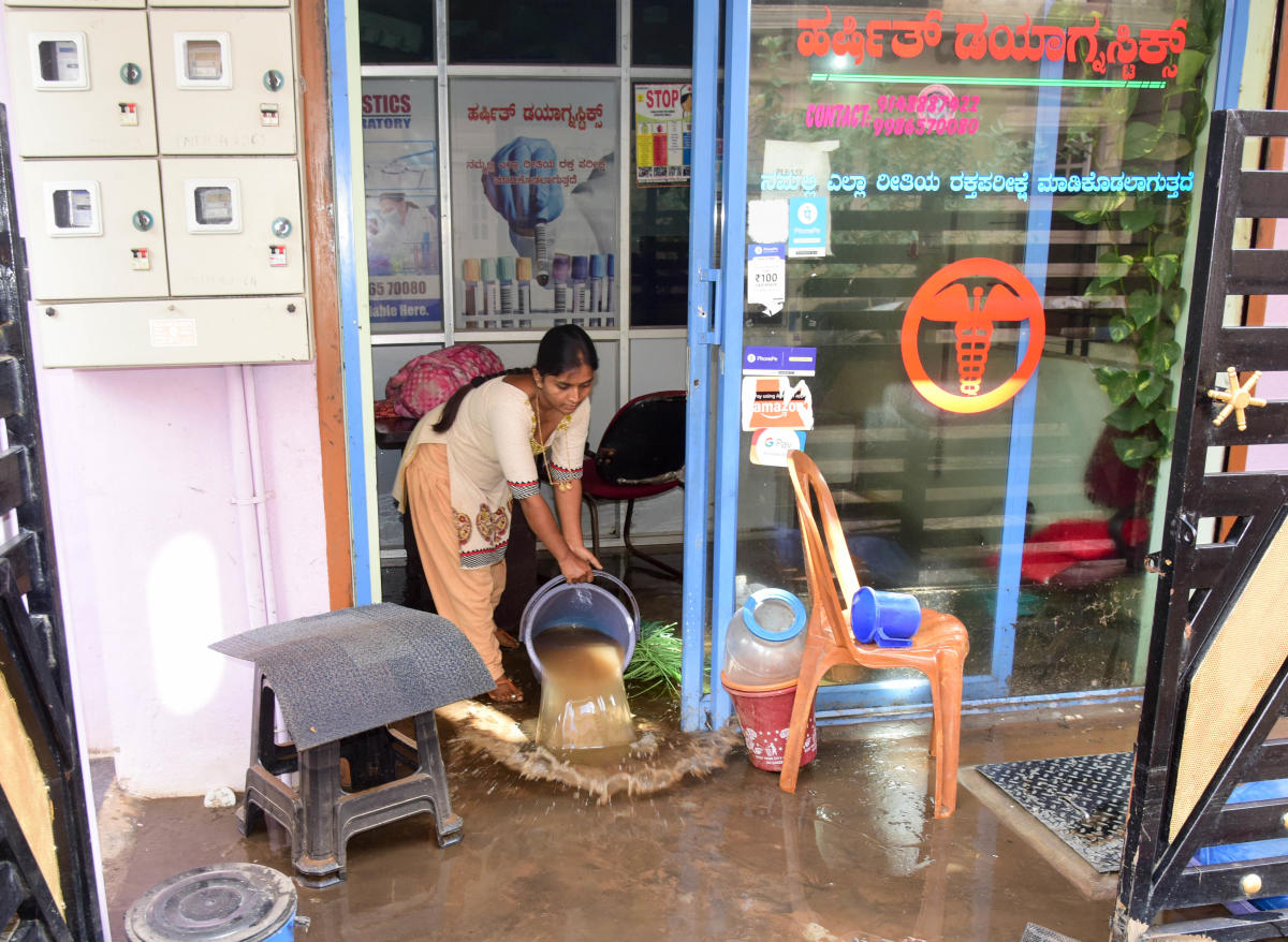 A woman clears out floodwater from her house in in Rukmini Nagar, T Dasarahalli, on Tuesday. DH PHOTO/B H SHIVAKUMAR