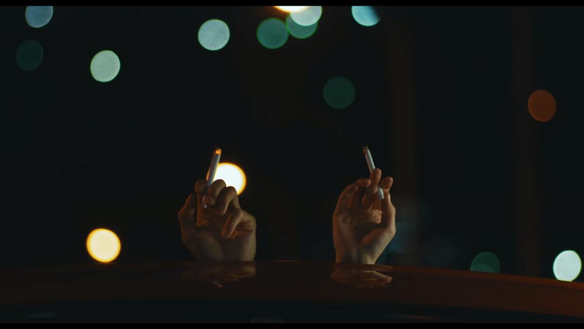 Yusuke and his driver Misaki share a smoke in Drive My Car (2021)