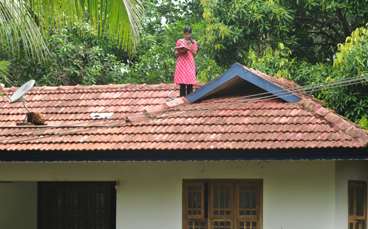 Namitha, a degree student of Malappuram, sitting on rooftop for good online connectivity for e-learning. Photo: Sakeer Hussain