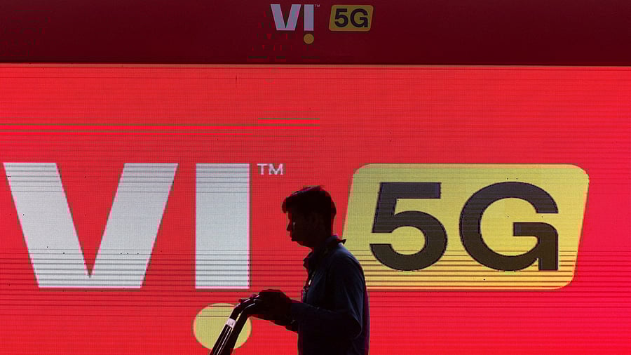 <div class="paragraphs"><p>A man walks across the LED display board showing the logo of Vodafone-Idea.&nbsp;</p></div>