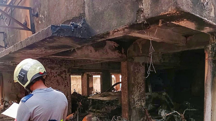 <div class="paragraphs"><p> A fire department personnel maintains records as charred vehicles are seen after a fire broke out in a multi-storey residential building in Goregaon area Mumbai, early Friday.</p></div>