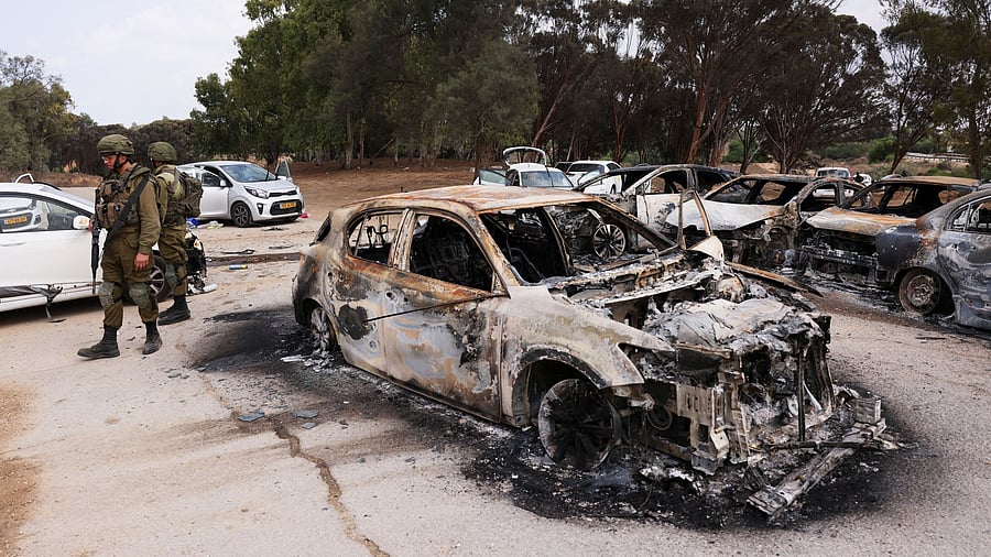<div class="paragraphs"><p>Israeli soldiers inspect burnt cars that were abandoned in a carpark near where a festival was held before an attack by Hamas gunmen from Gaza, by Israel's border with Gaza in southern Israel, October 10, 2023. </p></div>