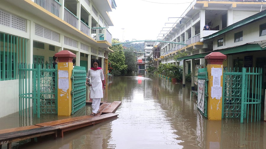 <div class="paragraphs"><p>Guwahati: A student walks on a temporary bridge at the waterlogged campus of a college after heavy rains, in Guwahati.</p></div>