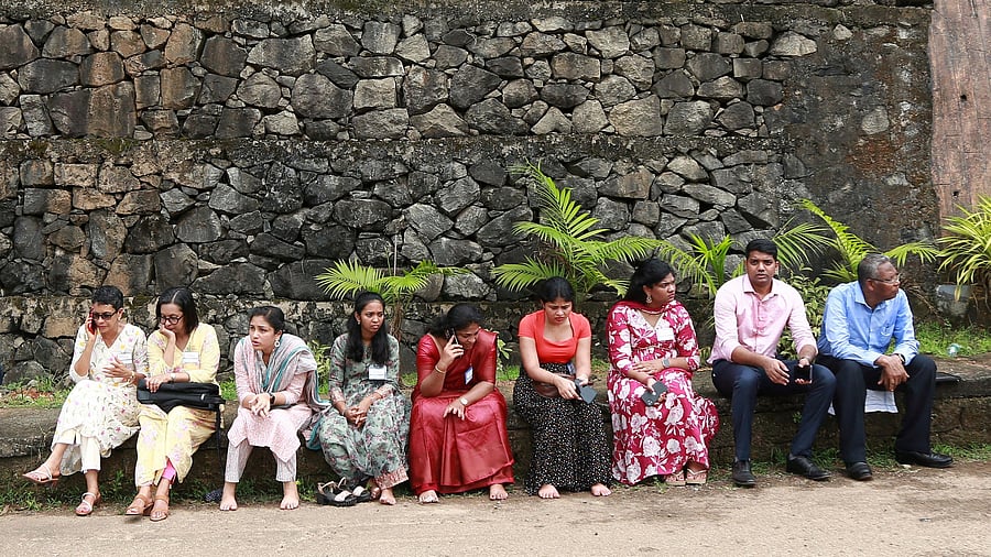<div class="paragraphs"><p>People sit outside the Zamra International Convention and Exhibition Centre after being evacuated from the centre following multiple blasts during a religious gathering of Jehovah's Witnesses, a Christian group, in Kochi</p></div>
