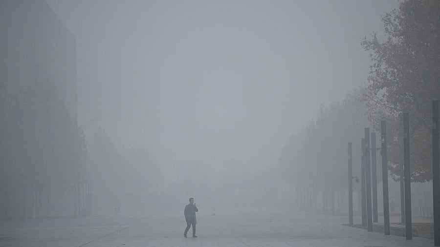 <div class="paragraphs"><p>A man uses his mobile phone as he walks amid smog in Tianjin after the city issued a yellow alert for air pollution, China.</p></div>