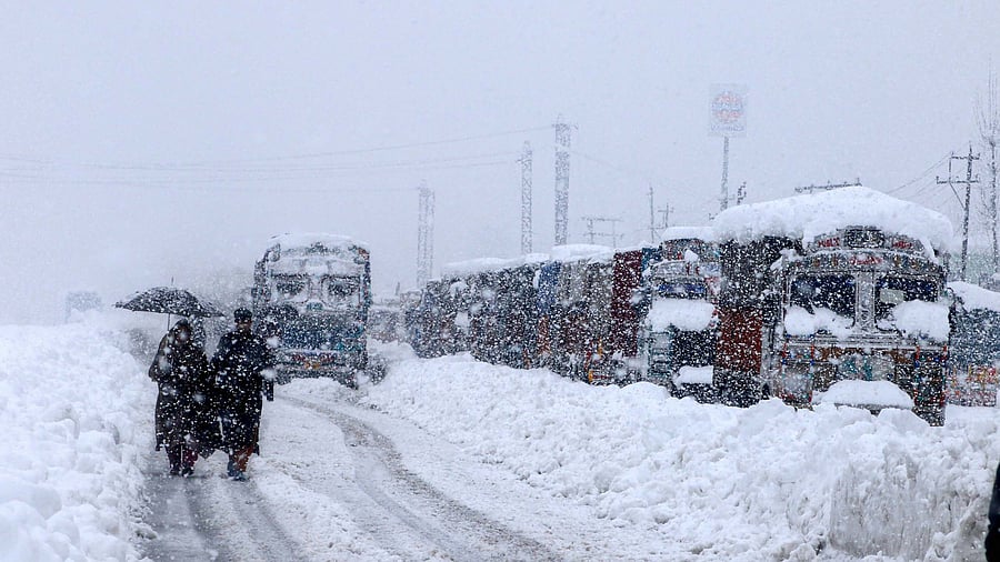 <div class="paragraphs"><p>People walk past stranded vehicles on the Jammu-Srinagar National Highway during heavy snowfall.&nbsp;</p></div>