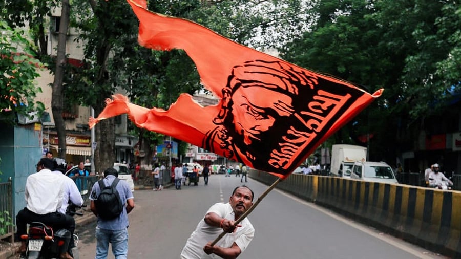 <div class="paragraphs"><p>A man waves a flag as he blocks a road during a protest, organised by Maharashtra state's Maratha community </p></div>