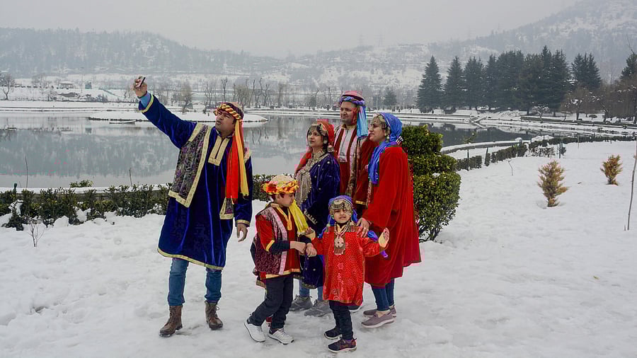 <div class="paragraphs"><p>Tourists wearing traditional Kashmiri dresses click a selfie, during their visit to the botanical gardens after winter snowfall, in Srinagar. </p></div>