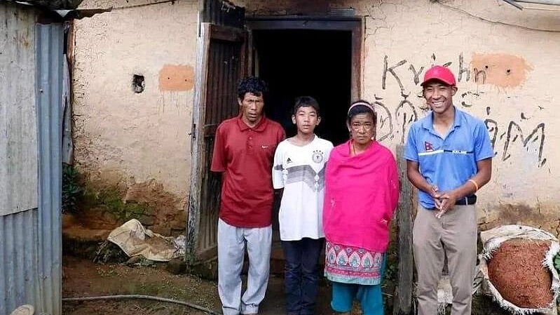 Golfer Subhash Tamang (right) with his family in front of their shack in Lalitpur, Nepal. The Nepal Golf Association raised money to build a solid house (in white) that is seen behind.