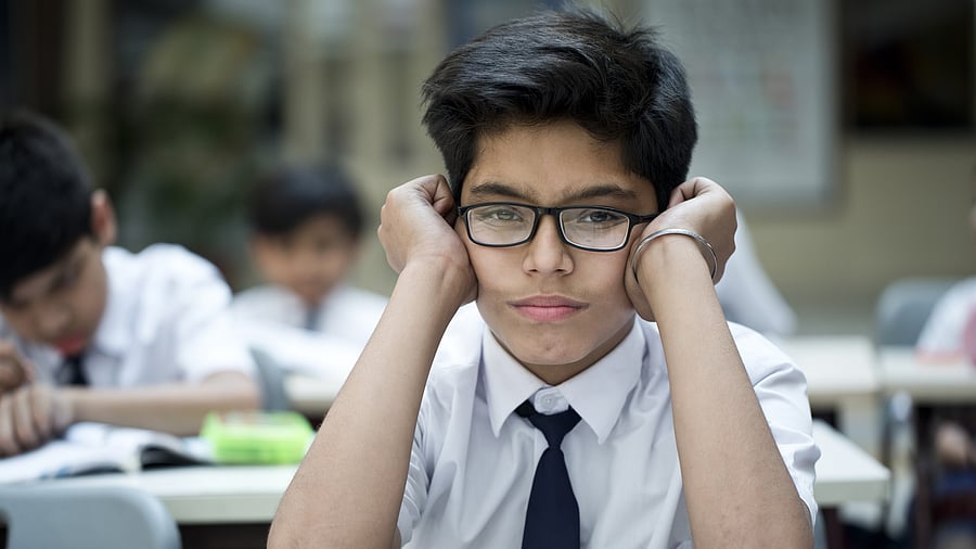 <div class="paragraphs"><p>School boy bored of studying in classroom.</p></div>