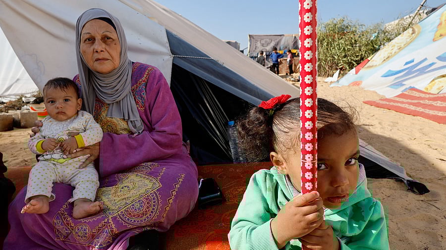 <div class="paragraphs"><p>A woman holds a baby next to a girl, as displaced Palestinians, who fled their houses due to Israeli strikes, shelter in a tent camp near the border with Egypt, amid the ongoing conflict between Israel and the Palestinian Islamist group Hamas, in Rafah in the southern Gaza Strip, December 11, 2023. </p></div>