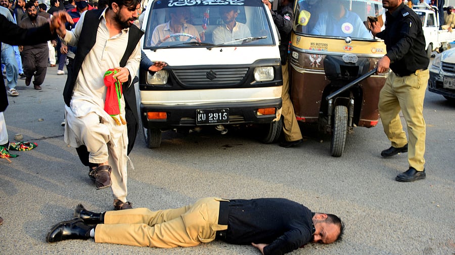 <div class="paragraphs"><p>An injured police officer lies on the road during a clash with supporters of former prime minister Imran Khan's party, the Pakistan Tehreek-e-Insaf, at a rally ahead of a general election, in Karachi, Pakistan. </p></div>
