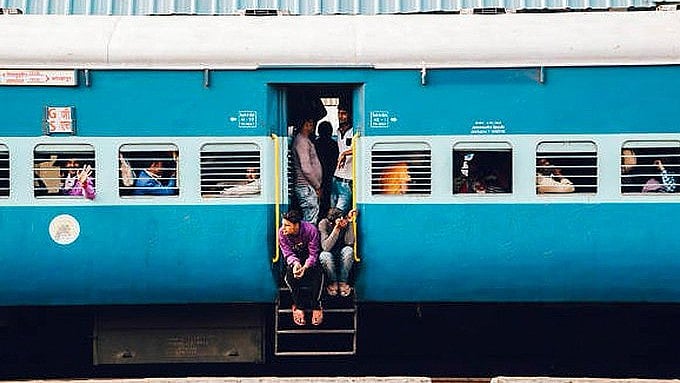 <div class="paragraphs"><p>Passengers sitting at the door of a train.</p></div>