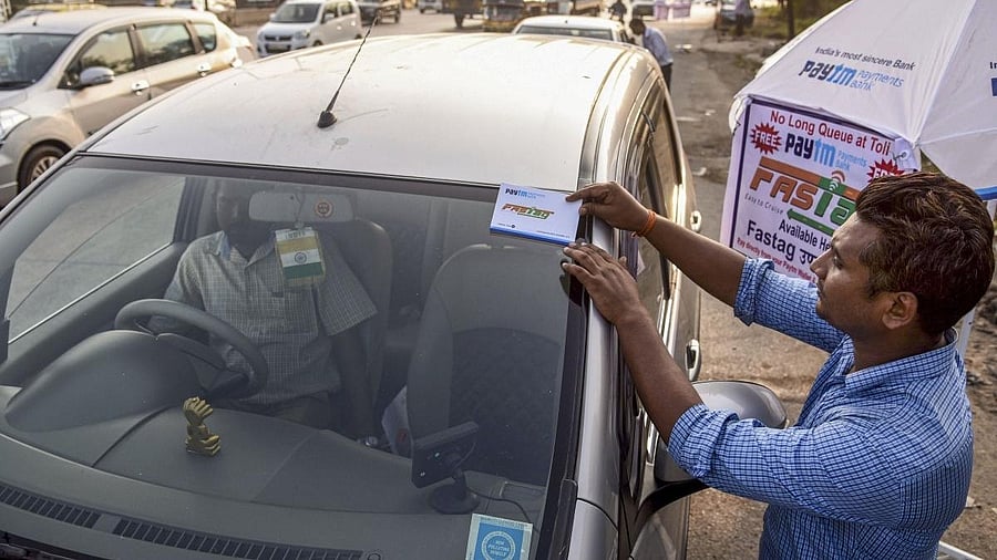 <div class="paragraphs"><p> A worker fixes a FASTag sticker on the windscreen of a car.</p></div>