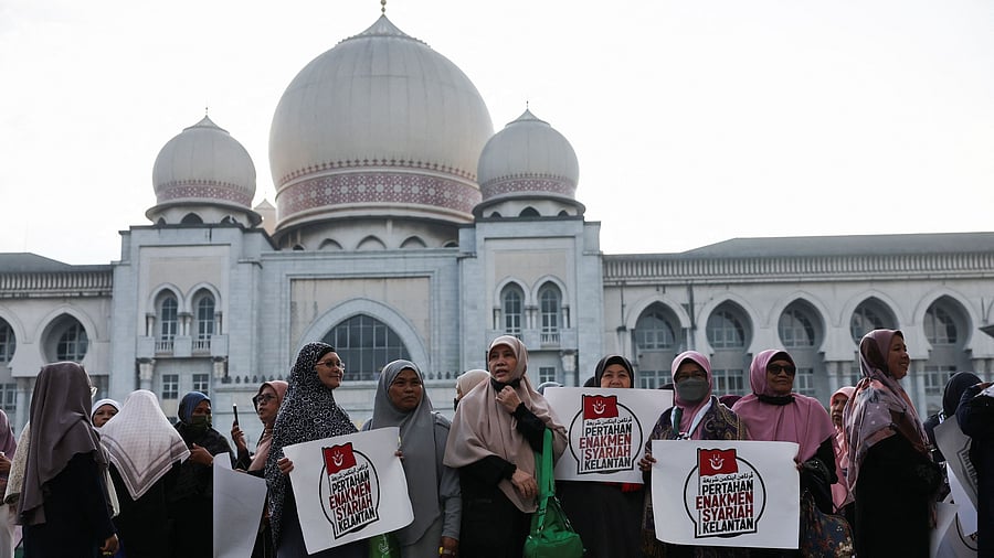 <div class="paragraphs"><p>Muslim women hold placards as they stand in protest outside the Palace of Justice on the day the country's federal court delivers verdict in a constitutional case challenging the legality of some Islamic laws in Kelantan state, in Putrajaya, Malaysia.</p></div>