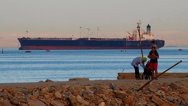 <div class="paragraphs"><p>People walk on the beach as a container ship crosses the Gulf of Suez towards the Red Sea.</p></div>