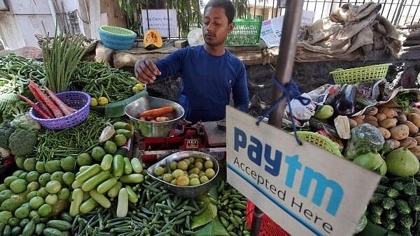 <div class="paragraphs"><p> A vendor weighs vegetable next to an advertisement of Paytm, the digital payments firm. </p></div>