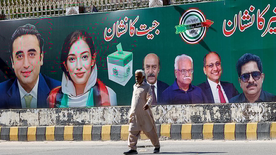 <div class="paragraphs"><p> A man walks next to a billboard displaying photos of politician Bilawal Bhutto and his sister Asifa Bhutto.</p></div>