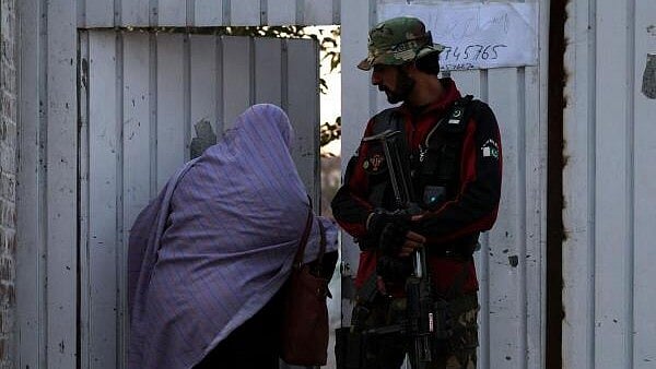 <div class="paragraphs"><p>A polling staff enters a polling station as a police officer stands guard in Gulbahar area in Peshawar, Pakistan, February 8, 2024.</p></div>