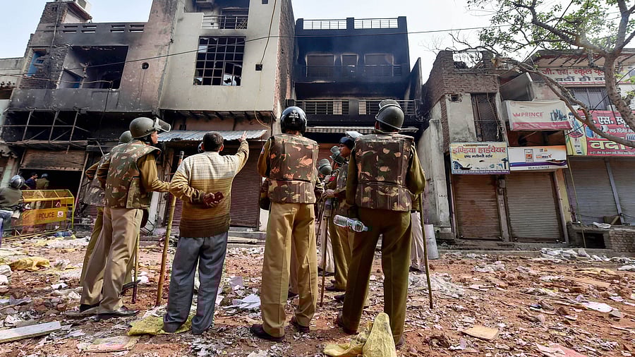 <div class="paragraphs"><p>Police personnel stand in front of a razed house in Delhi, Feb 26, 2020.</p></div>
