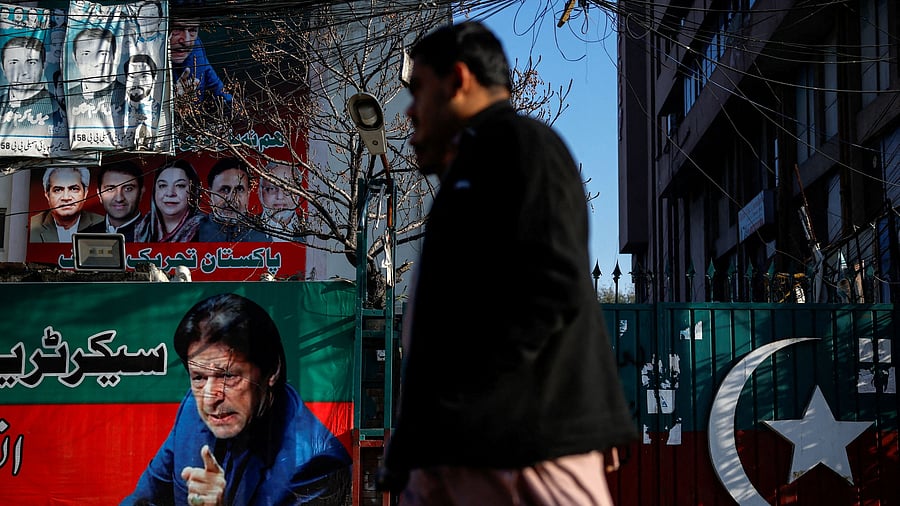 <div class="paragraphs"><p>People walk past a banner with a picture of the former Prime Minister Imran Khan outside the party office of Pakistan Tehreek-e-Insaf.</p></div>