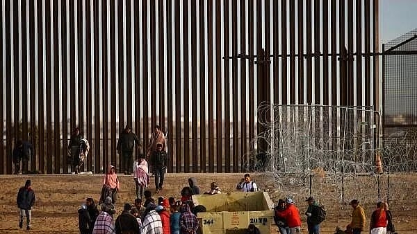 <div class="paragraphs"><p>Migrants gather near the border wall after crossing a razor wire fence deployed to inhibit their crossing into the US.</p></div>