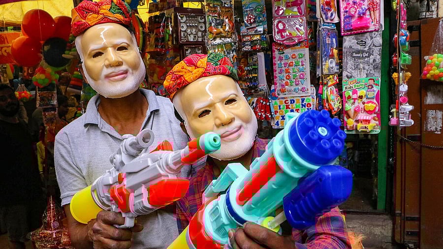 <div class="paragraphs"><p>Vendors wearing masks of Prime Minister Narendra Modi hold water guns at a shop ahead of the festival of Holi.</p></div>