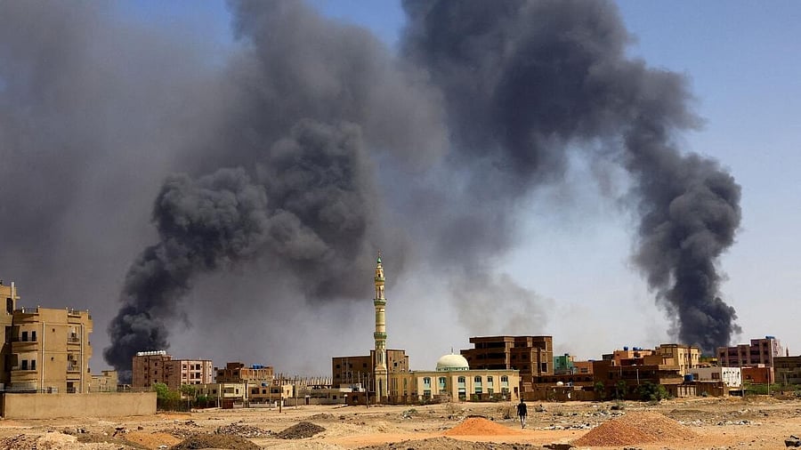 <div class="paragraphs"><p>A man walks while smoke rises above buildings after aerial bombardment, during clashes between the paramilitary Rapid Support Forces and the army in Khartoum North, Sudan.</p></div>