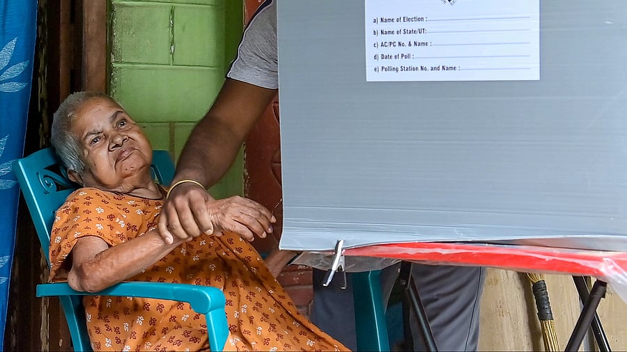 <div class="paragraphs"><p>A volunteer assists a senior citizen to cast her vote via postal ballot at her house.</p></div>