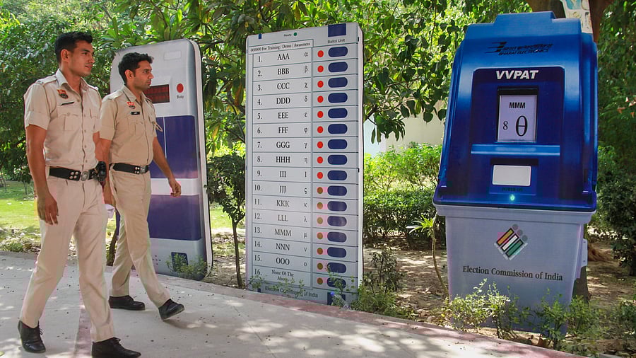 <div class="paragraphs"><p>Police personnel near standees of an Electronic Voting Machine (EVM) and VVPAT machine installed by the Election Commission of India (ECI).</p></div>