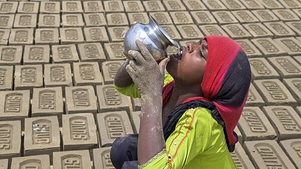 <div class="paragraphs"><p> A labourer drinks water to quench her thirst during a hot summer day, in Nadia.</p></div>