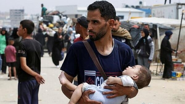 <div class="paragraphs"><p>A man carries a child, as Palestinians travel on foot along with their belongings as they flee Rafah due to an Israeli military operation, in Rafah, in the southern Gaza Strip, May 28, 2024.</p></div>