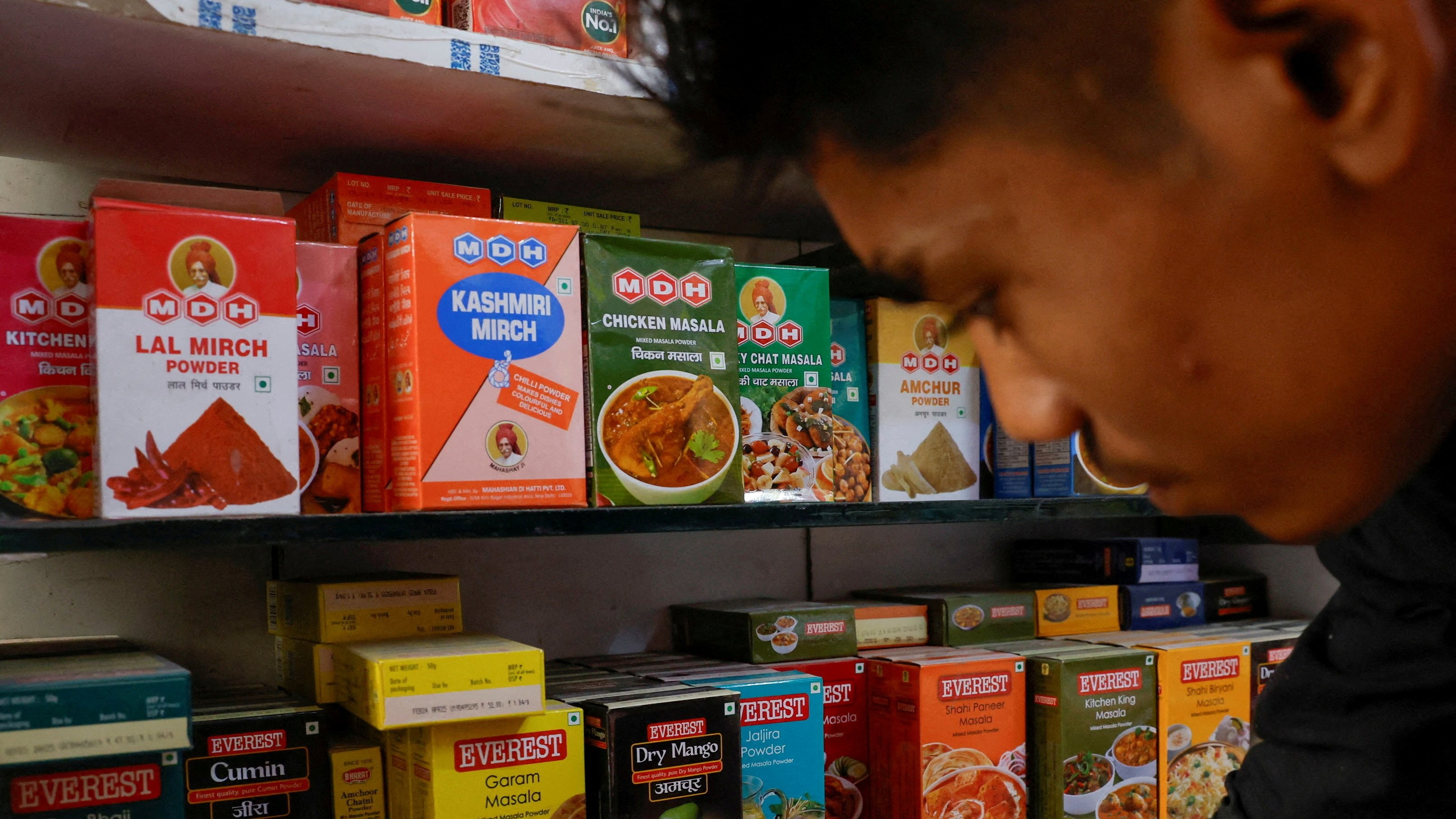 <div class="paragraphs"><p> A man stands near the spice boxes of MDH and Everest kept on the shelf of a shop at a market in New Delhi, April 29, 2024. </p></div>