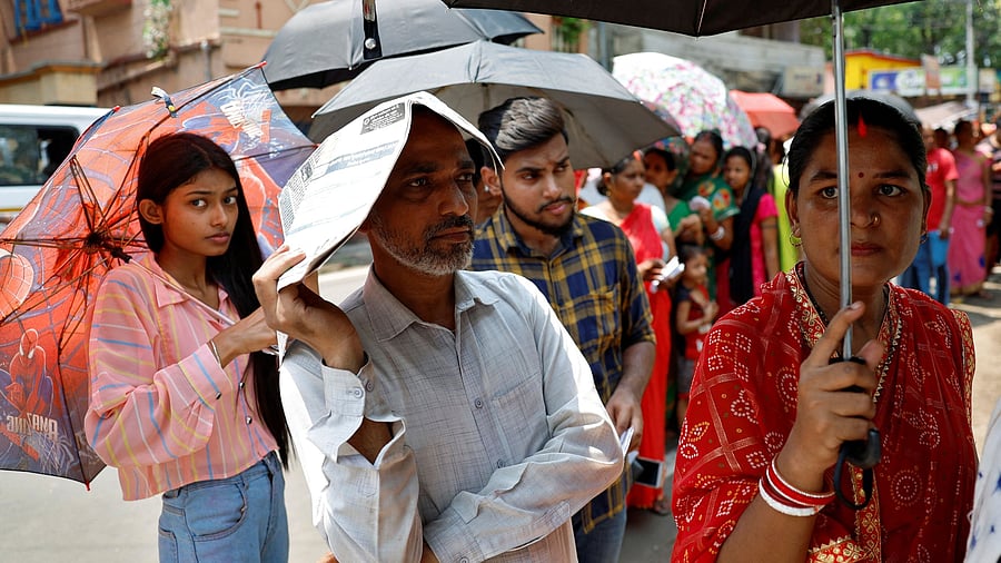 <div class="paragraphs"><p>A man uses a newspaper as others use umbrellas to protect themselves from the heat as they wait to vote outside a polling station.</p></div>