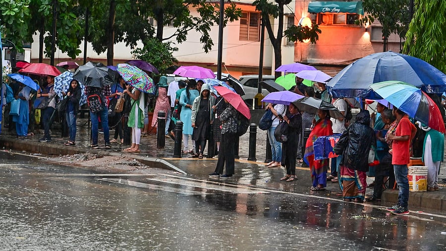 <div class="paragraphs"><p>Commuters wait at a bus stop on the Brigade Road and Residency Road Junction in the city. </p></div>