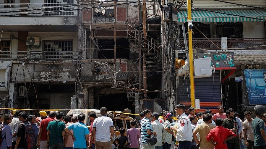 <div class="paragraphs"><p>People stand in front of a baby care hospital where several newborns died in a fire, in New Delhi.</p></div>