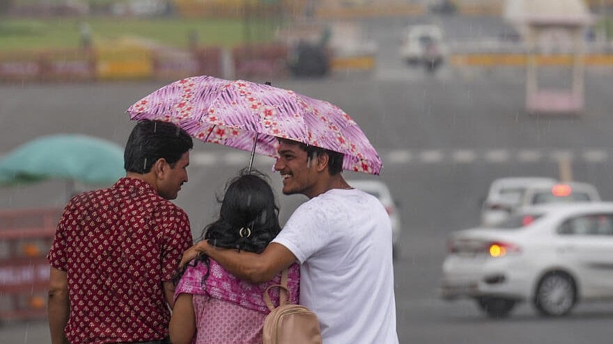 <div class="paragraphs"><p>Three people share an umbrell as they walk down the Kartavya Path amid rains.</p></div>