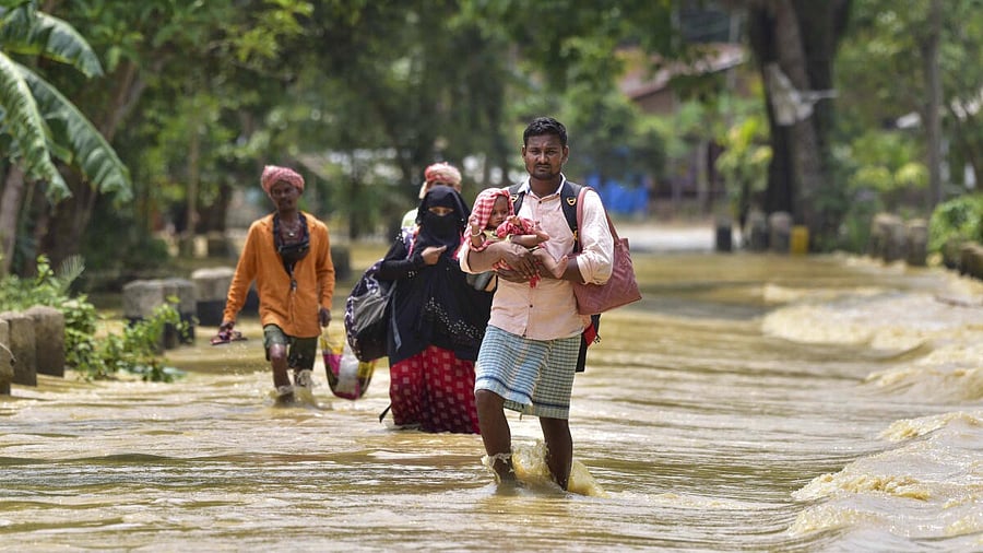 <div class="paragraphs"><p>People carry their belongings as they walk through a flooded road following rains after the landfall of cyclone 'Remal', in Nagaon district of Assam.</p></div>