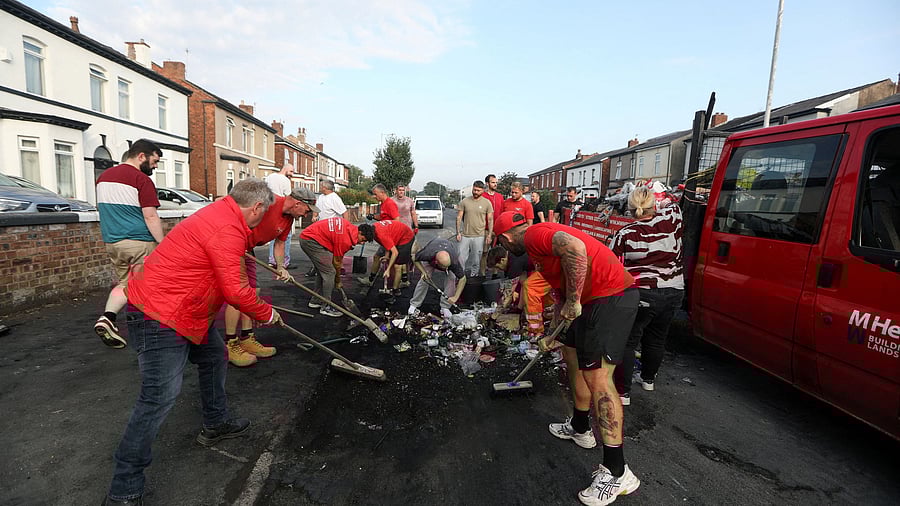 Volunteers sweep Sussex road, after violent protest following a vigil for victims of the knife attack in Southport, Britain July 31, 2024. REUTERS/Temilade Adelaja