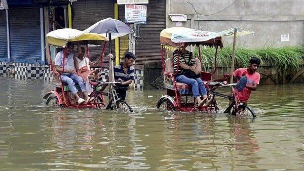 <div class="paragraphs"><p>Rickshaw pullers wade through a flooded street after rainfall, in Guwahati.</p></div>