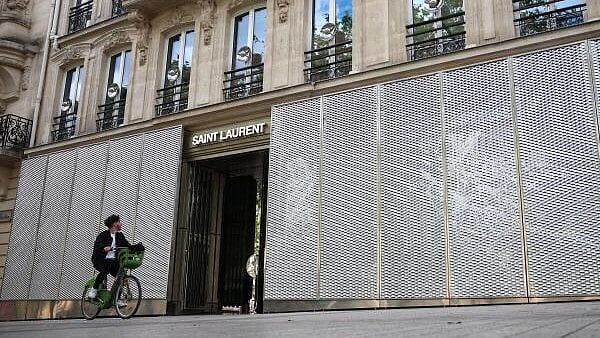 <div class="paragraphs"><p>A man rides his bicycle past protected windows of Saint Laurent's store on the Champs-Elysees avenue during the second round of the early French parliamentary election, in Paris, France, July 7, 2024.</p></div>