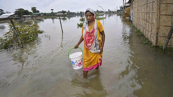 <div class="paragraphs"><p>A woman walks through a flood-affected area, in Nagaon district of Assam. </p></div>