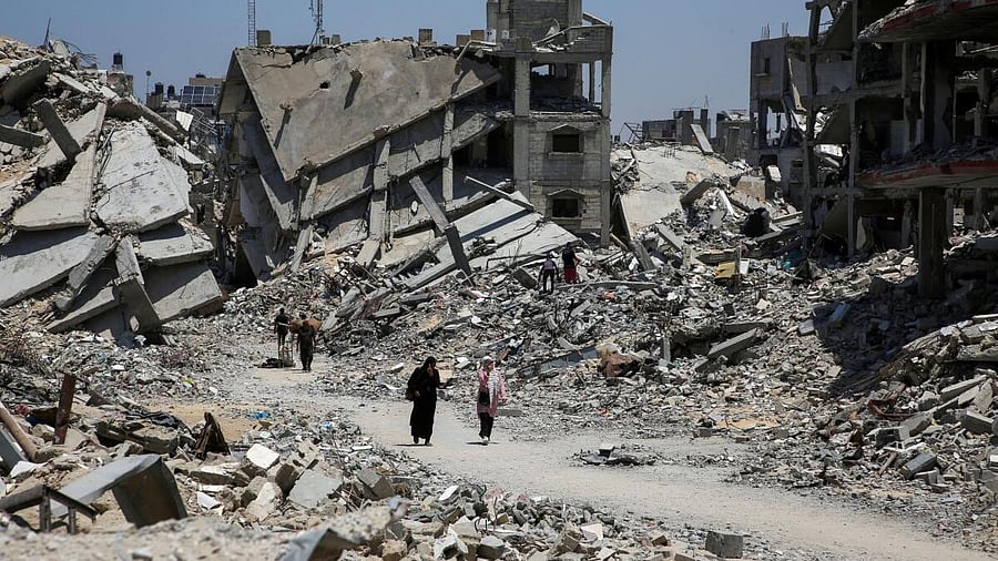 <div class="paragraphs"><p>Palestinians walk past the rubble of houses destroyed during the Israeli military offensive, amid Israel-Hamas conflict, in Khan Younis in the southern Gaza Strip on July 10, 2024.</p></div>