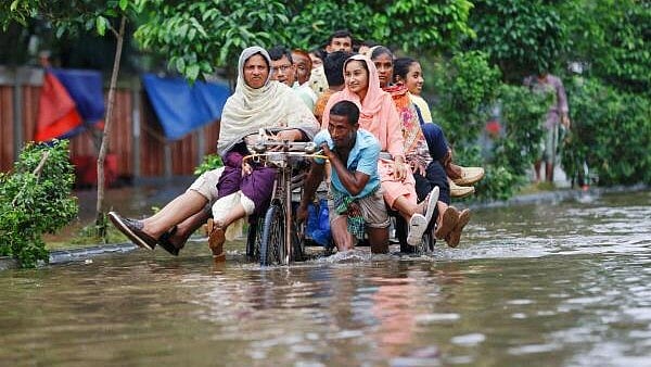 <div class="paragraphs"><p>In this file photo, commuters ride on a rickshaw on a flooded road after heavy rains in Dhaka, Bangladesh.</p></div>