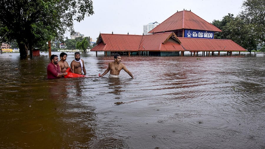 <div class="paragraphs"><p>People make their way through a flooded area near the Aluva Mahadeva Temple which got partially submerged due to rising water levels of the Periyar river following heavy rains, in Kochi.</p></div>