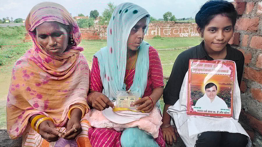 <div class="paragraphs"><p>Devotees sit with a picture of preacher Suraj Pal alias Sakar Hari alias Bhole Baba at his 'ashram'.</p></div>
