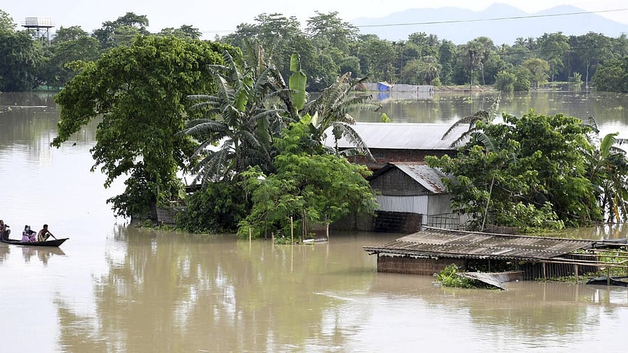 <div class="paragraphs"><p>People on a boat move past houses submerged in the floodwater, in Morigaon district in Assam. </p></div>