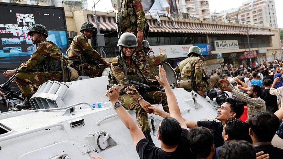 <div class="paragraphs"><p>People shake hands with army personnel as they celebrate the resignation of Bangladeshi Prime Minister Hasina in Dhaka.</p></div>